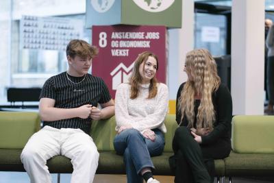 Tre elever fra hhv.  Lyngby Handelsgymnasium, Lyngby Gymnasium og Lyngby Handelsskole og sidder sammen på en sofa og taler