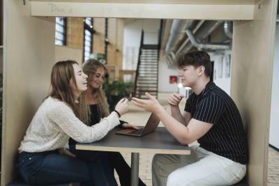 HHX elever, to piger og en dreng griner under gruppearbejde på Lyngby Handelsgymnasium