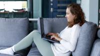 Kvinde sidder i sofa og får online undervisning