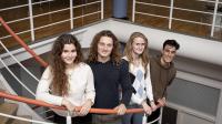 Fire gymnasieelever står på en trappe og smiler