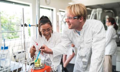 To elever med kitler på laver eksperiment i fysiklokalet