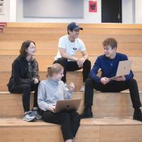 Fire elever fra HHX i Lyngby sidder på en trappe med deres computer og taler sammen